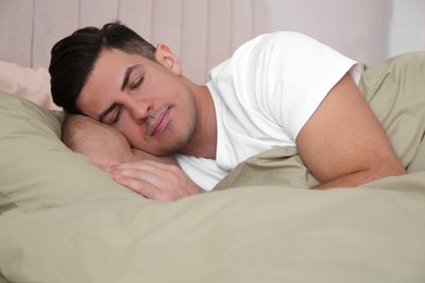Photo of Man sleeping in comfortable bed with green linens