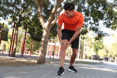 Photo of Man in sportswear having knee problems on sports ground