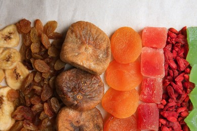Different tasty dried fruits on paper, flat lay