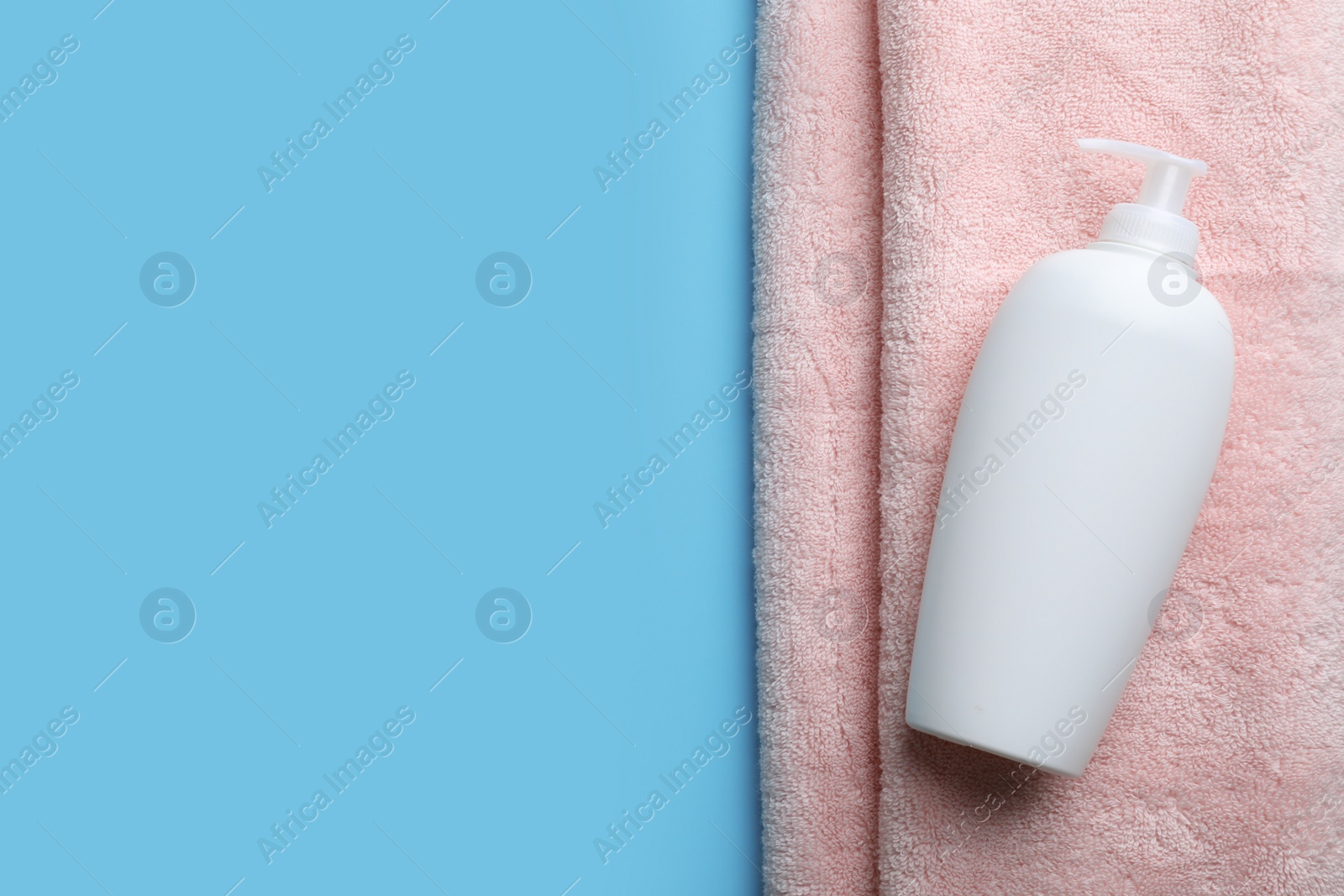 Photo of Bottle of shampoo and towel on color background, top view with space for text