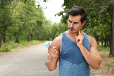 Young man checking pulse with medical device after training in park. Space for text