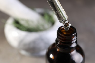 Photo of Dripping dill essential oil from pipette into bottle on blurred background, closeup. Space for text