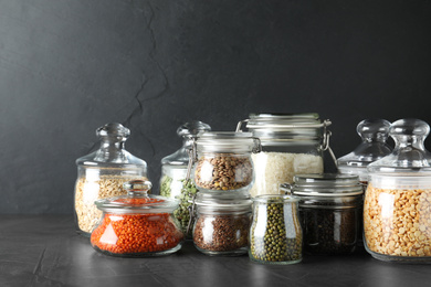 Photo of Different types of legumes and cereals on dark grey table. Organic grains