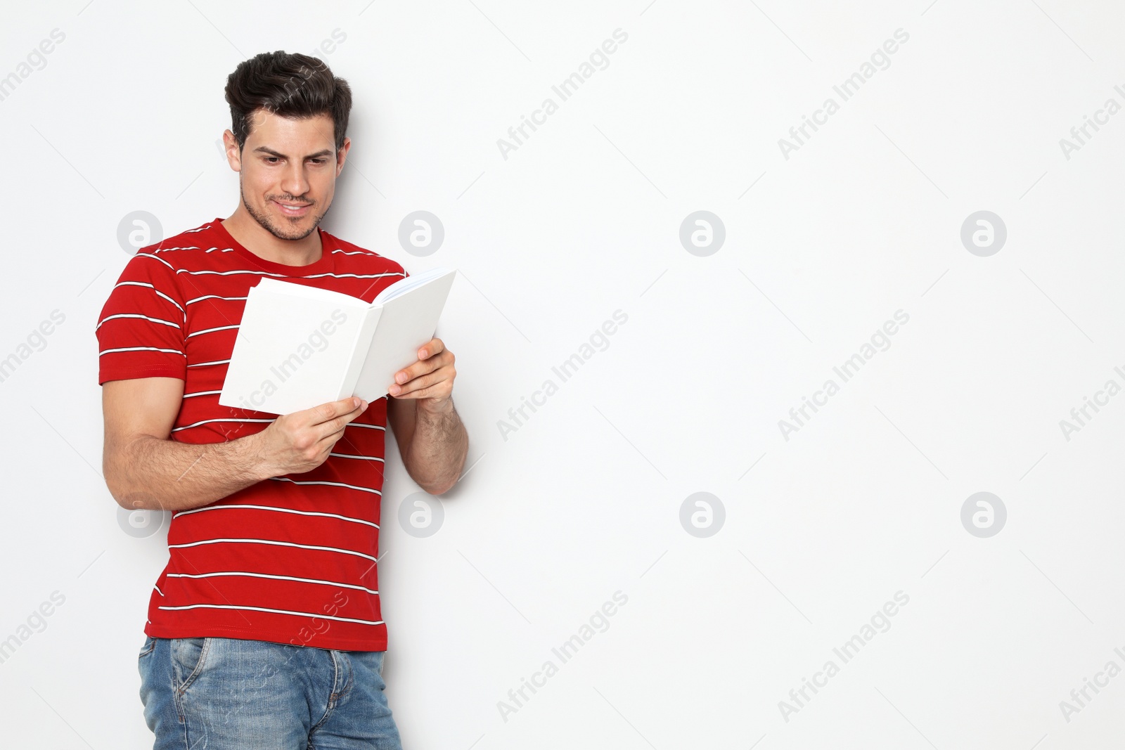 Photo of Handsome man reading book on white background, space for text