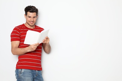 Photo of Handsome man reading book on white background, space for text