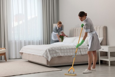 Professional chambermaids cleaning up bedroom in hotel