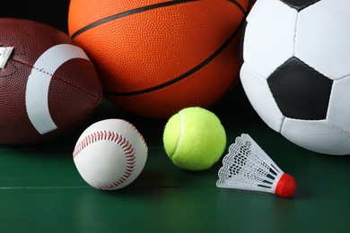 Photo of Set of different sport balls and shuttlecock on green wooden surface