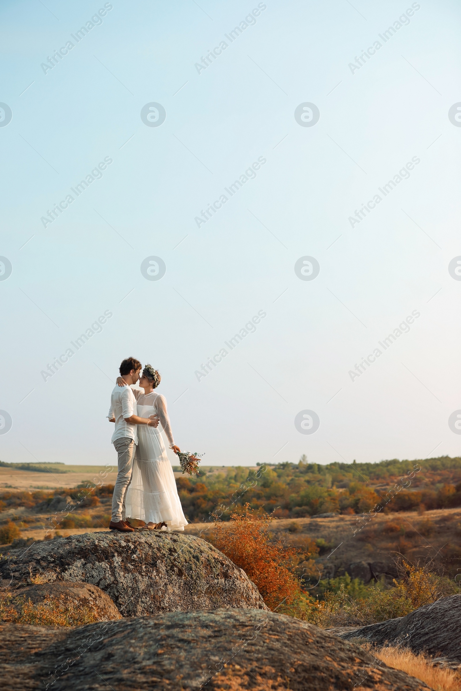 Photo of Happy newlyweds with beautiful field bouquet outdoors