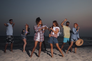 Photo of Happy friends enjoying summer beach party in evening