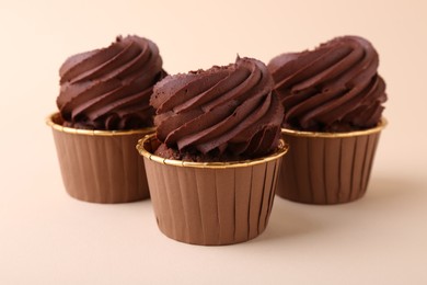 Photo of Delicious chocolate cupcakes on beige background, closeup