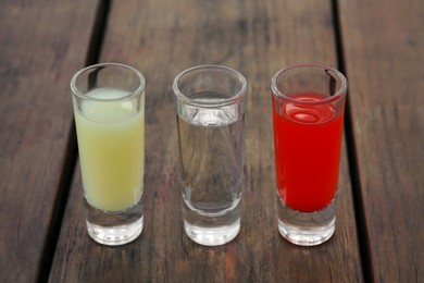 Photo of Shots with lime juice, tequila and sangria as colors of mexican flag on wooden table, closeup. Traditional serving