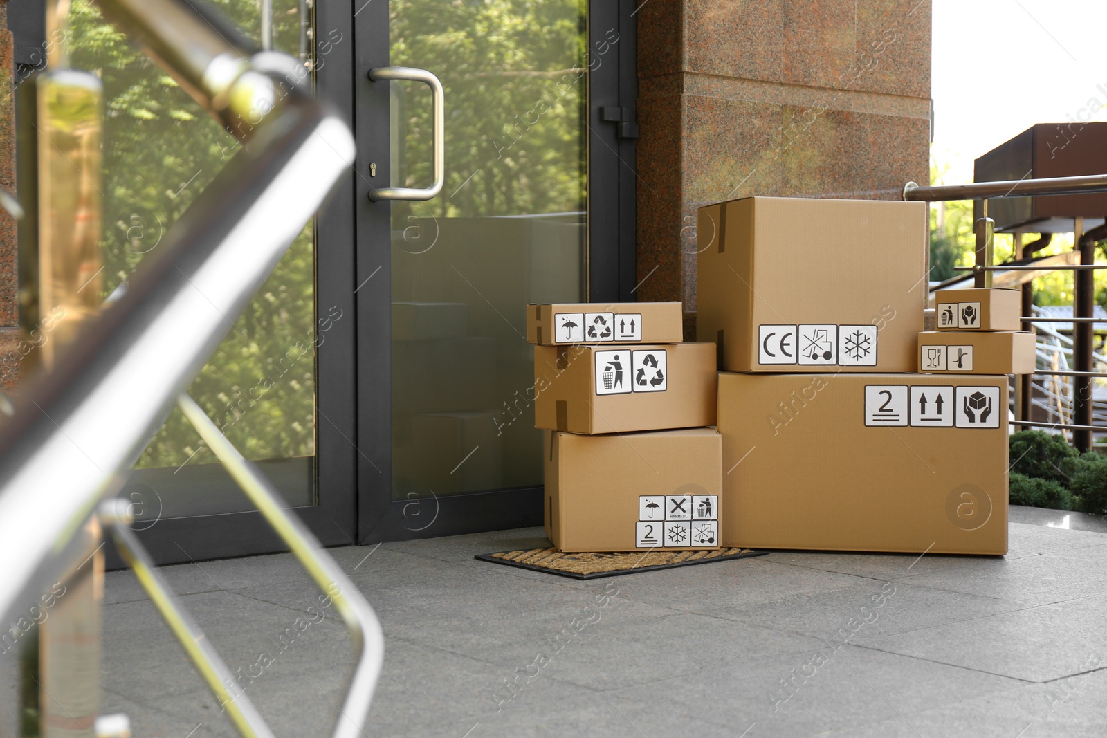 Photo of Cardboard boxes with different packaging symbols on door mat near entrance. Parcel delivery