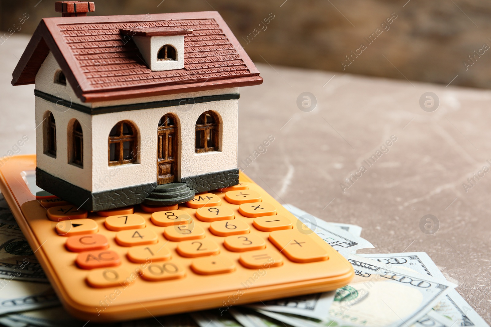 Photo of House model with calculator and money on table, closeup. Real estate agent service