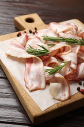 Slices of raw bacon and spices on wooden table, closeup