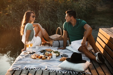 Photo of Happy couple spending time on pier at picnic