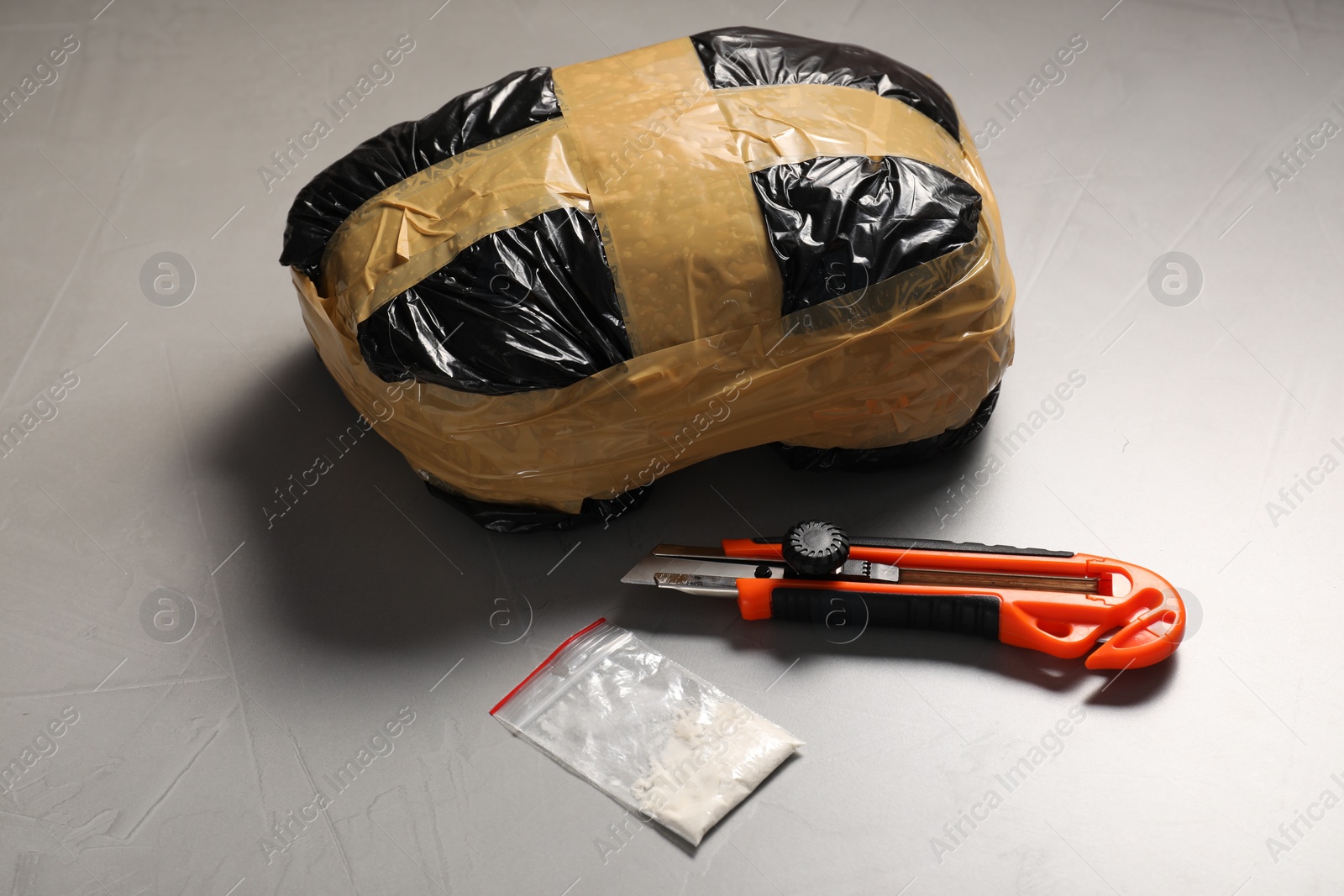 Photo of Packages with narcotics and stationery knife on grey textured table