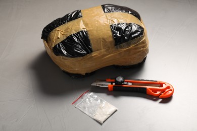 Photo of Packages with narcotics and stationery knife on grey textured table