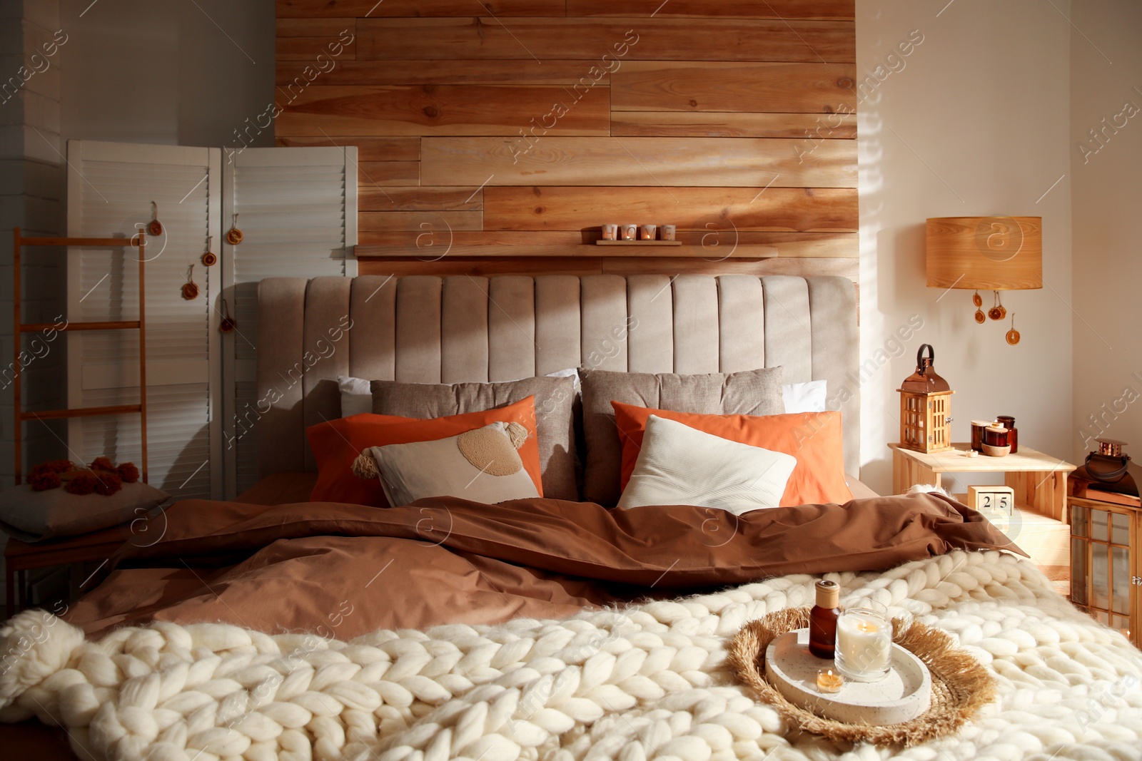 Photo of Cozy bedroom interior with knitted blanket and cushions