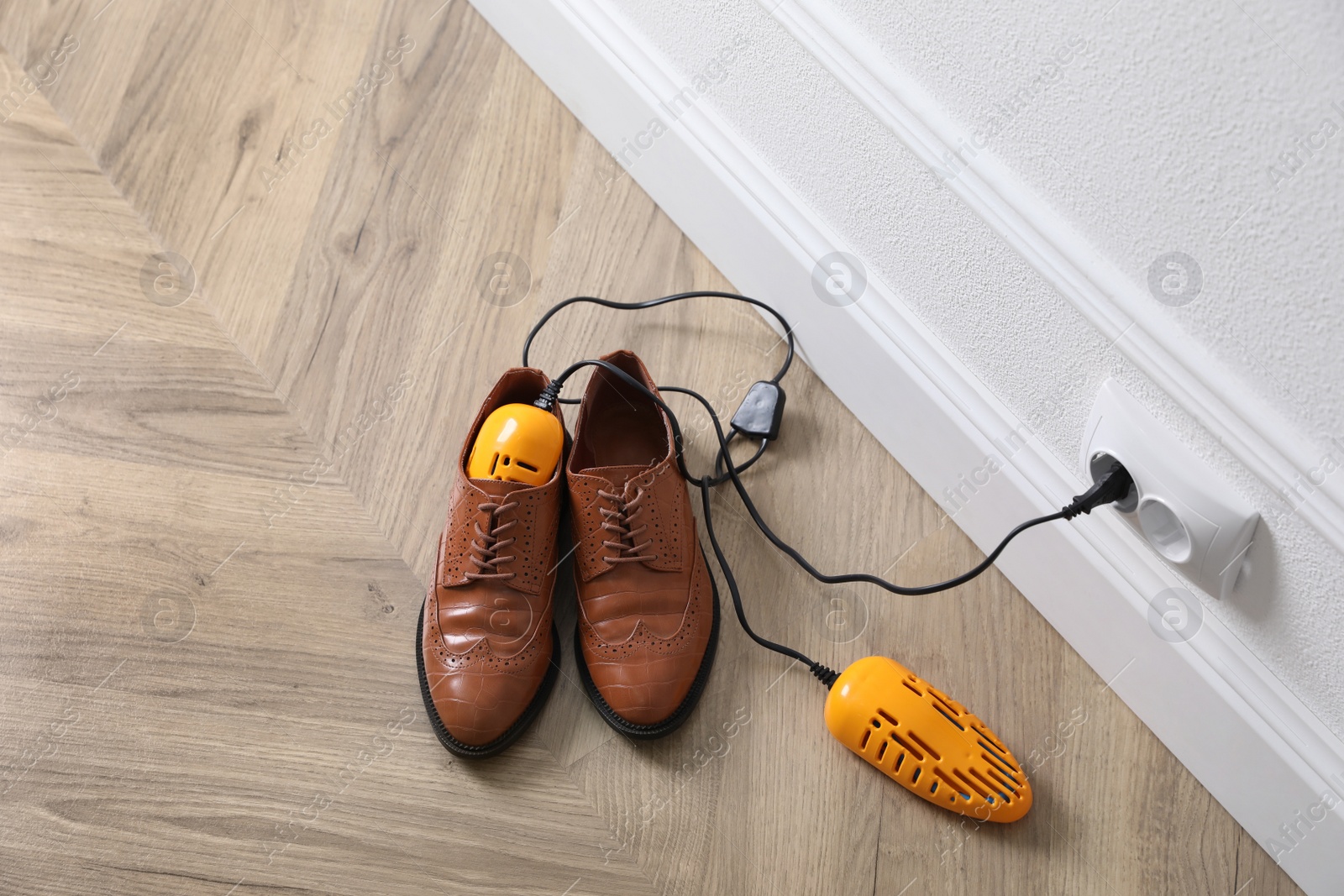 Photo of Pair of stylish shoes with modern electric footwear dryer on floor indoors, above view