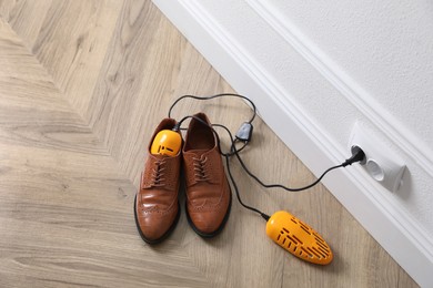 Photo of Pair of stylish shoes with modern electric footwear dryer on floor indoors, above view