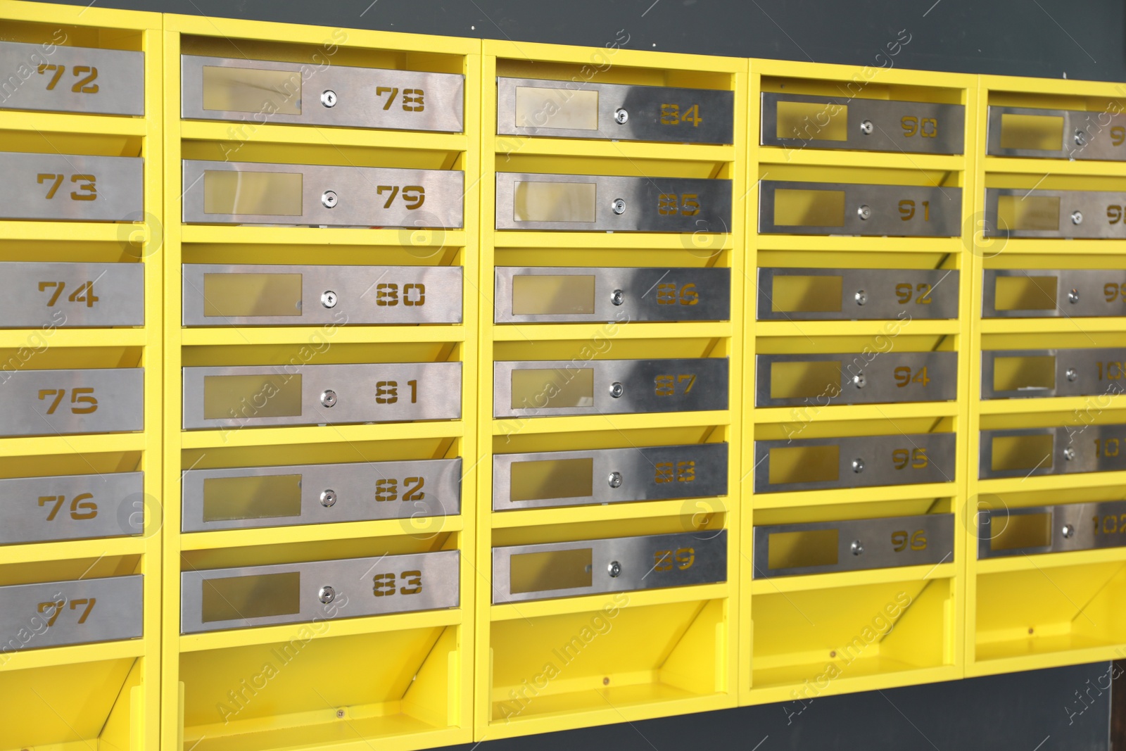 Photo of Many closed metal mailboxes with keyholes and numbers in post office