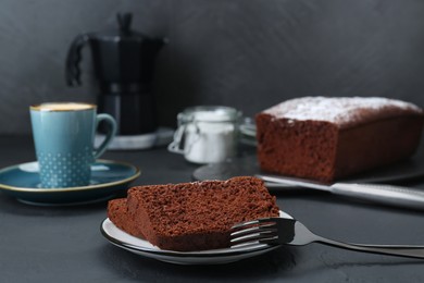 Photo of Pieces of tasty chocolate sponge cake on black table. Space for text