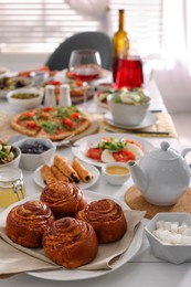Photo of Delicious buns and many different dishes served on buffet table for brunch