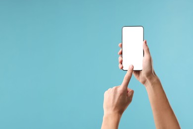 Photo of Man using smartphone with blank screen on light blue background, closeup. Mockup for design