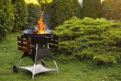 Photo of Portable barbecue grill with fire flames outdoors. Space for text
