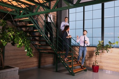 Group of coworkers talking during coffee break on stairs in office