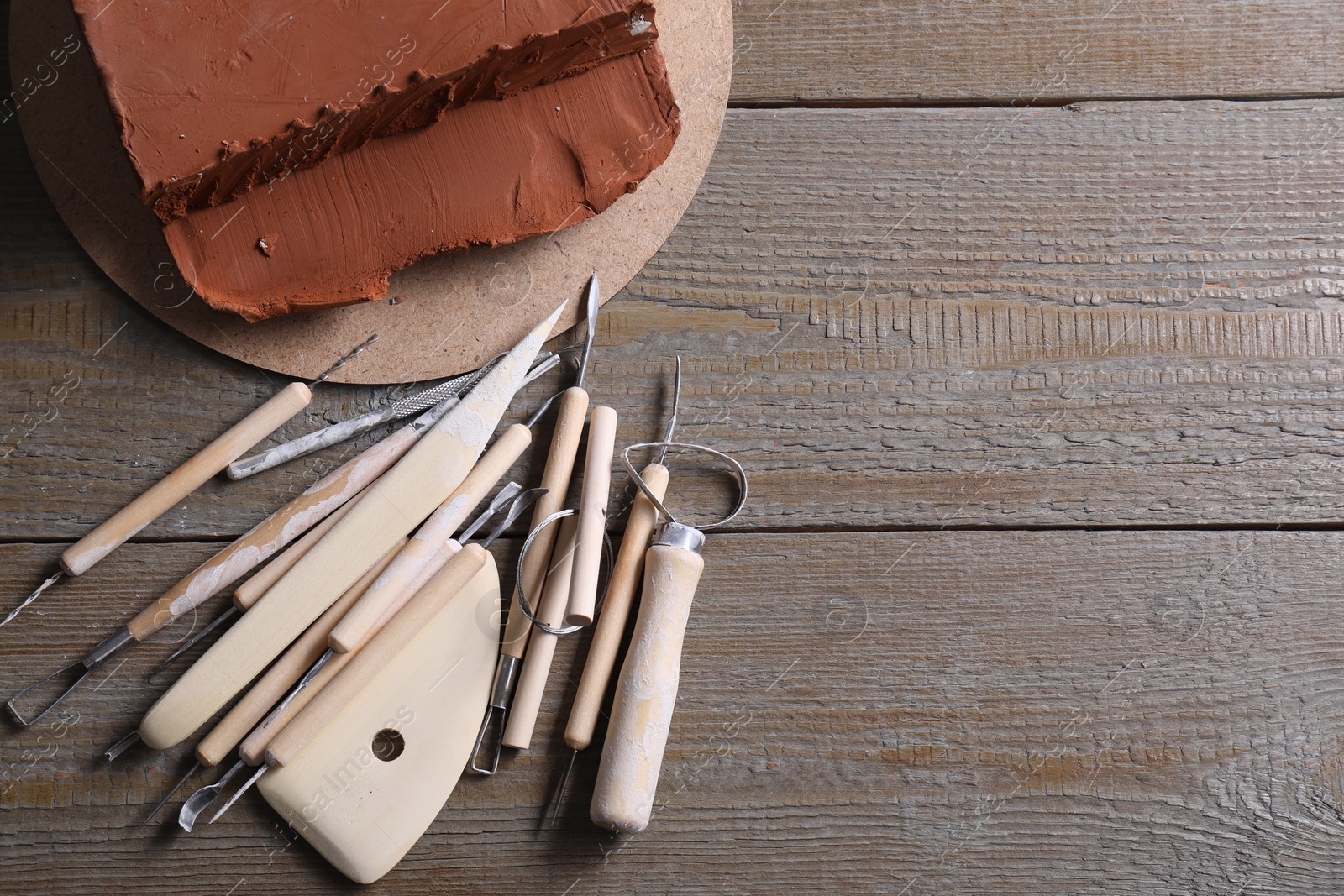 Photo of Clay and set of modeling tools on wooden table, flat lay. Space for text