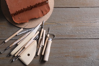 Photo of Clay and set of modeling tools on wooden table, flat lay. Space for text