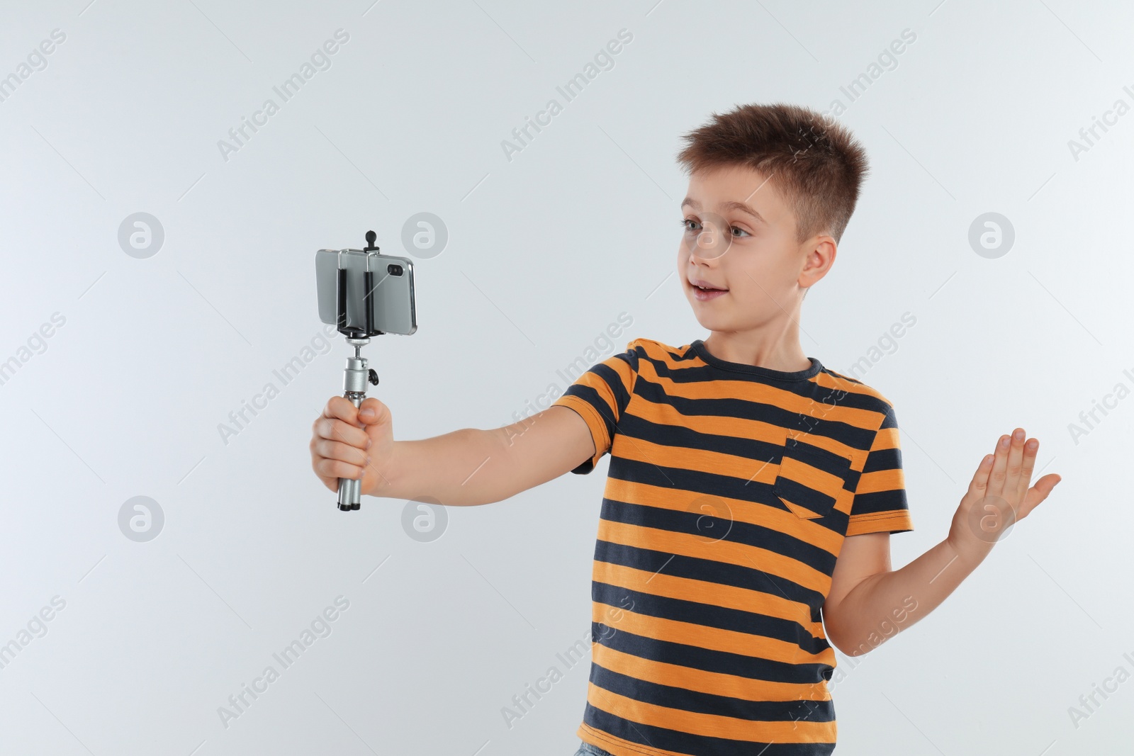 Photo of Cute little blogger recording video on white background