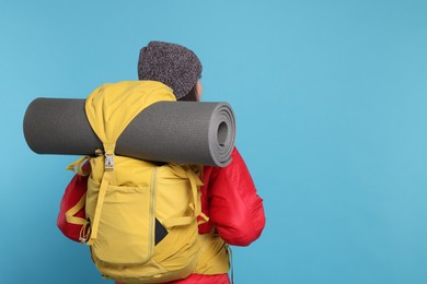 Photo of Woman with backpack and mat on light blue background, space for text. Active tourism
