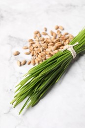 Sprouts of wheat grass and seeds on white marble table, closeup