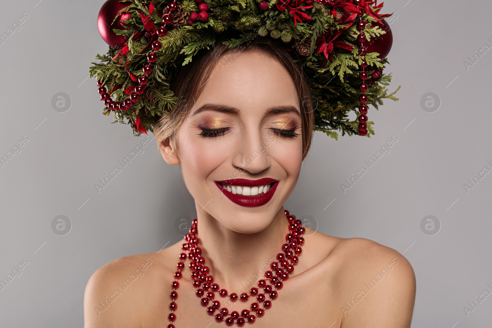 Photo of Beautiful young woman wearing Christmas wreath on grey background