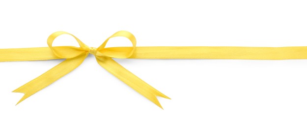 Yellow satin ribbon with bow on white background, top view