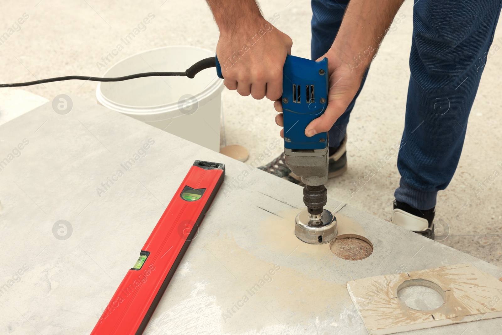 Photo of Worker making socket hole in tile indoors, closeup