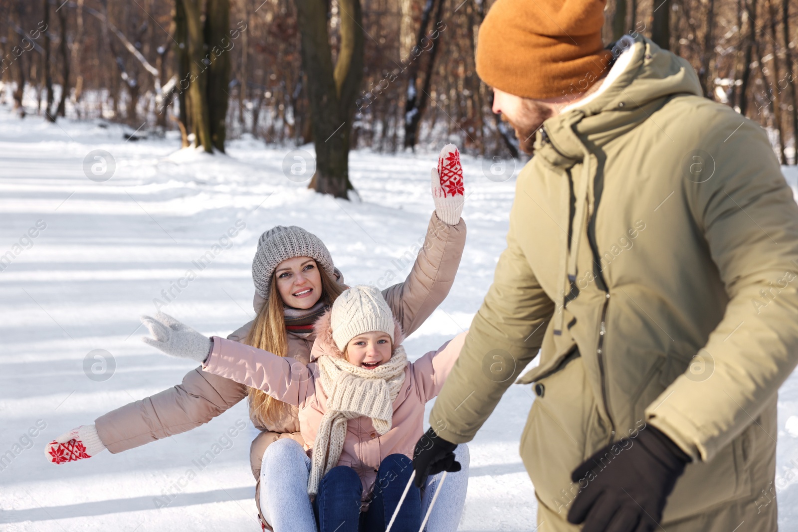 Photo of Happy family having fun with sledge in snowy forest