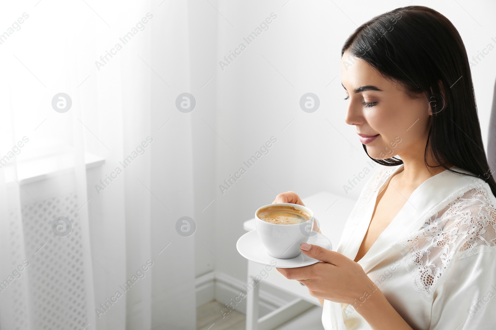 Photo of Woman with cup of coffee in bedroom. Lazy morning