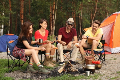 People having lunch with sausages near camping tent outdoors