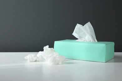 Photo of Used paper tissues and box on white table