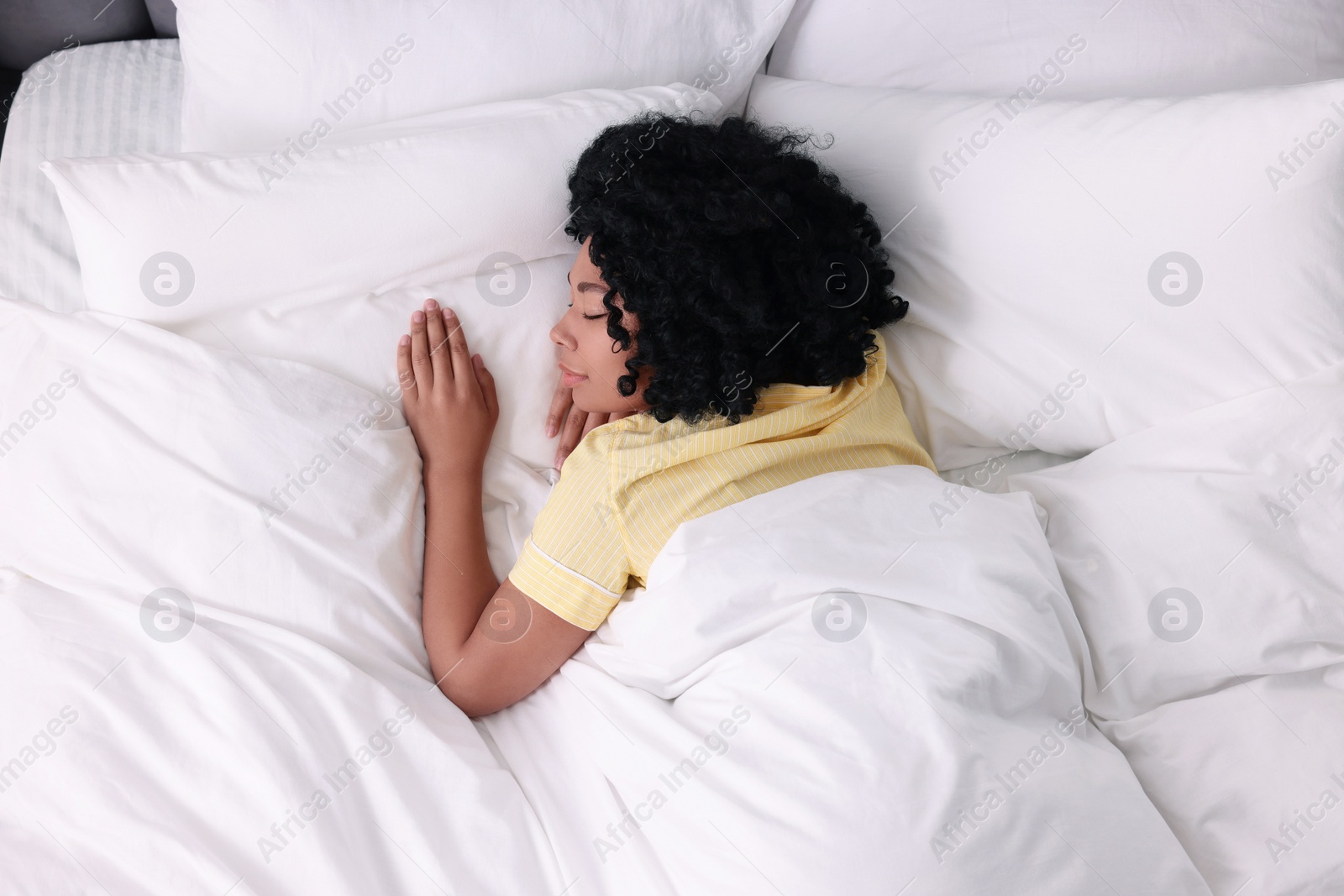 Photo of Beautiful young woman sleeping in soft bed, above view