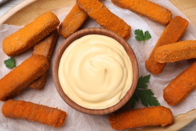 Photo of Delicious chicken nuggets and cheese sauce with parsley on plate, top view