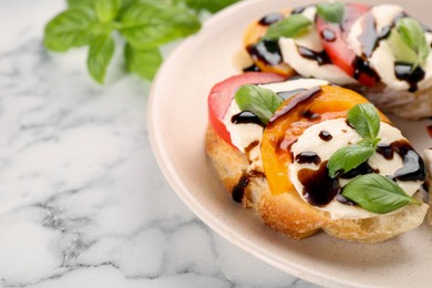 Photo of Delicious bruschettas with mozzarella cheese, tomatoes and balsamic vinegar on white marble table, closeup. Space for text