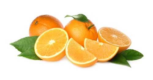 Cut and whole fresh ripe oranges with green leaves on white background