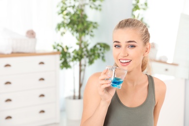 Photo of Woman rinsing mouth with mouthwash in bathroom. Teeth care