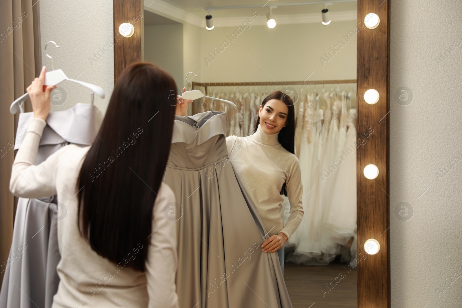 Photo of Woman choosing dress in rental clothing salon