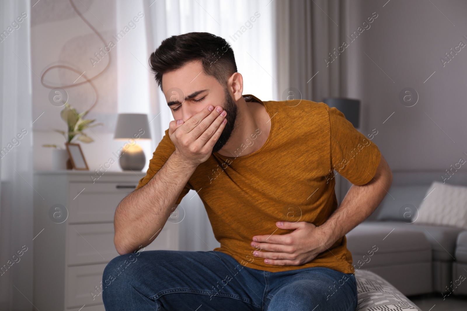 Photo of Young man suffering from nausea at home. Food poisoning