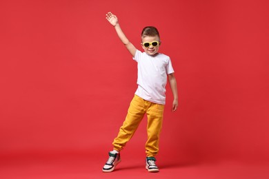 Photo of Happy little boy dancing on red background
